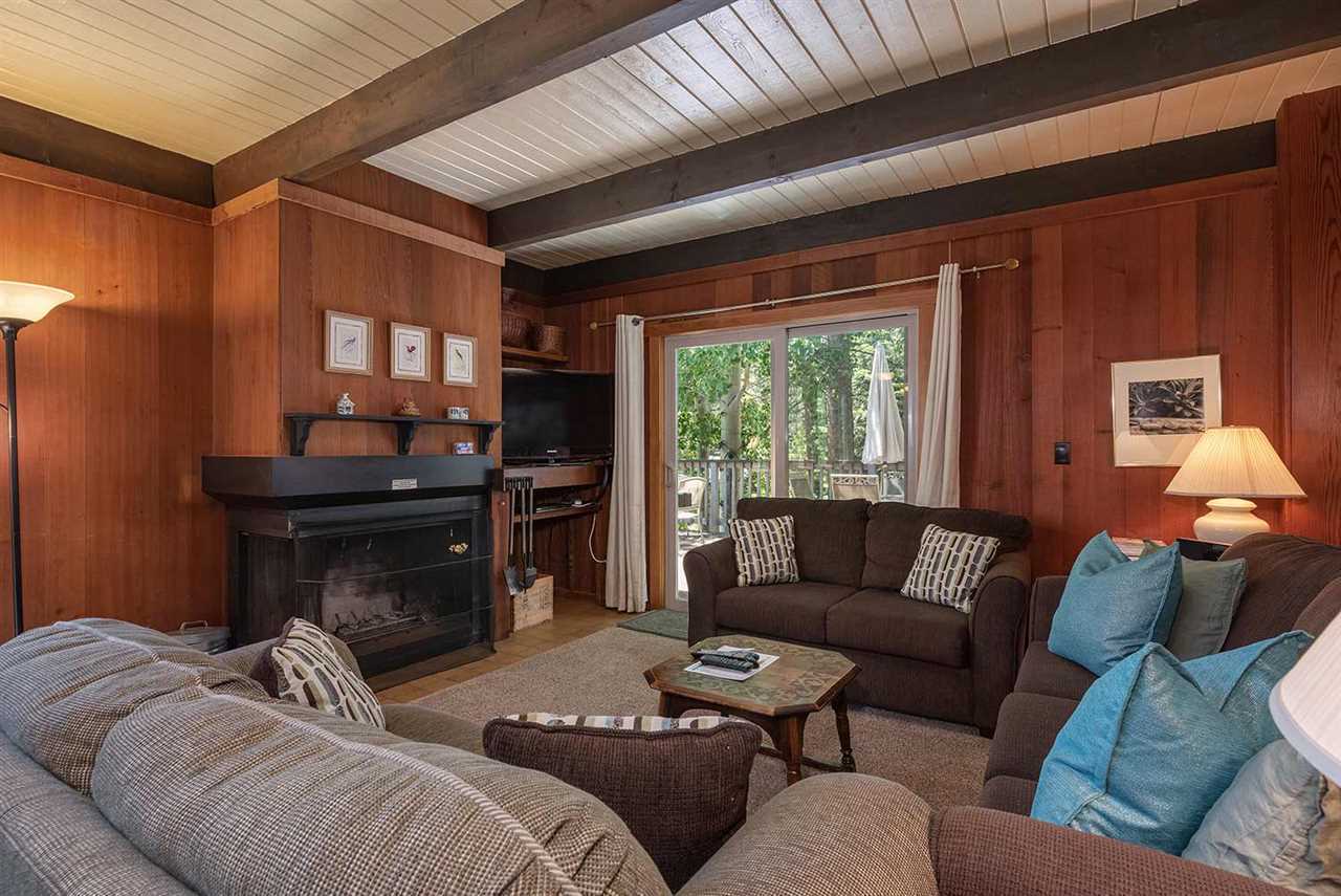 Open-concept great room with vaulted ceilings, gas fireplace, and forest views inside the Palisades Tahoe vacation cabin in Olympic Valley